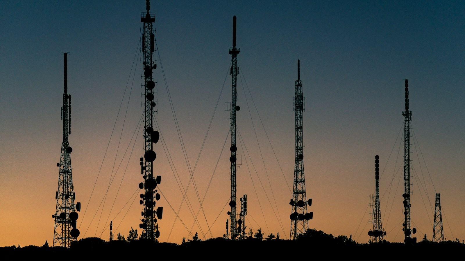 Telecom towers silhouetted against a sunset sky